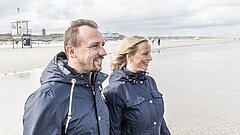 Mann und Frau am Strand von Juist schauen aufs Meer und genießen die Meeresluft