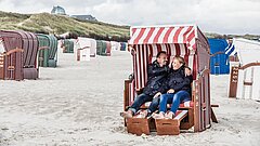 Paar in einem Strandkorb mit Ortszentrum im Hintergrund auf Juist