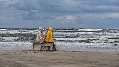 Zwei Personen auf einer Bank am Strand von Juist im Winter vor der Nordsee