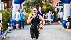 Läuferin beim Insellauf einem Wettkampf auf Juist mit dem Ziel / Startpunkt im Hintergrund und Flasche in der Hand