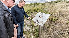 Beispiel einer Infotafel an einem Thalassoweg auf der Strandpromenade Juist mit interessierten Nutzenden