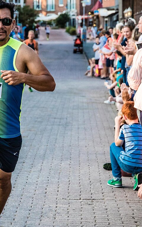 Zieleinlauf beim Juister Insellauf, Mann im Vordergrund, Publikum am Bildrand