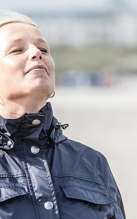 Frau am Strand genießt ihren Wellnessurlaub auf Juist