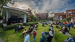 Open Air Veranstaltungen auf dem Kurplatz auf Juist, zu sehen ist die Bühne auf dem Kurplatz von der Seite mit Zuschauern auf Bänken
