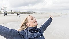Frau am Strand auf Juist atmet tief ein