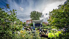 Open Air Veranstaltungen auf dem Kurplatz auf Juist, man schaut durch Begrünung in Richtung Bühne und von hinten damit auf die Zuschauer