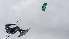 Kite surfer auf Juist führt einen Trick vor und fliegt durch die Luft