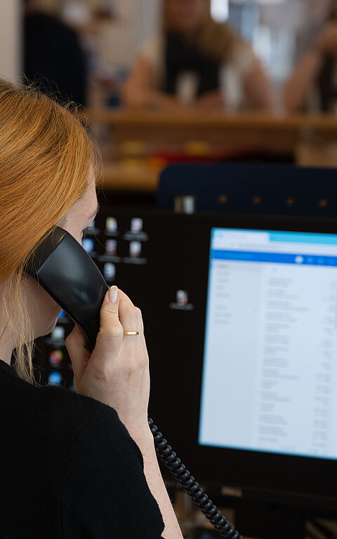 Beratung am Telefon mit Frau am Telefon und Display in der Tourist-Information im Rathaus auf Juist