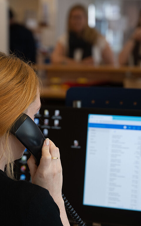 Beratung am Telefon mit Frau am Telefon und Display in der Tourist-Information im Rathaus auf Juist