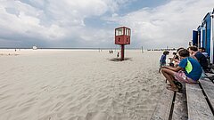 Treffpunkt des Strandsports auf Juist ist der Rote Rettungsturm Nummer 2 am Strand, blaue Container am Bildrand mit ein paar jungen Leuten, die auf den Beginn eines Events warten