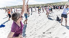 Frau im Vordergrund mit Sportgruppe im Hintergrund bei der Strandgymnastik auf Juist