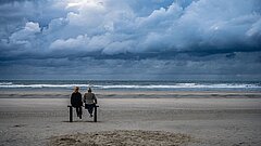 Breiter Strand auf Juist mit zwei Personen auf einer Bank in der Entfernung