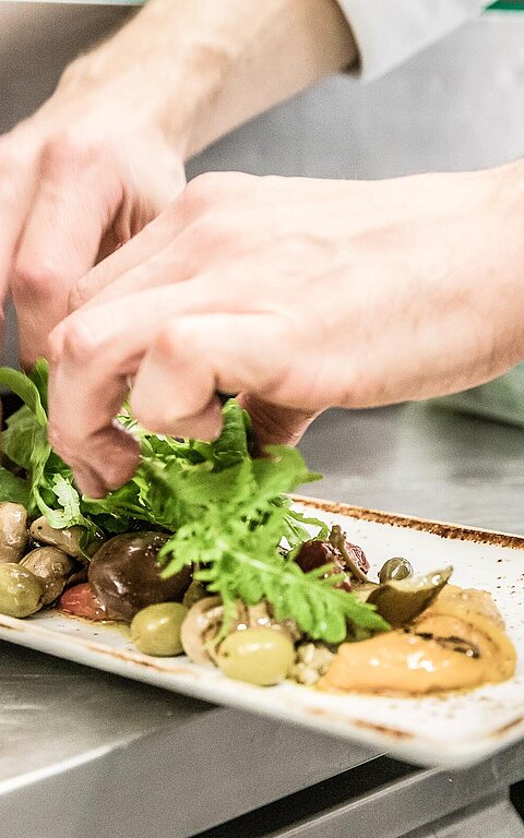 Essen und Trinken auf Juist - eine Person richtet Essen in einer Küche an
