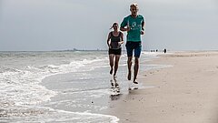 zwei Personen joggen am Strand auf Juist direkt an der Wasserkante